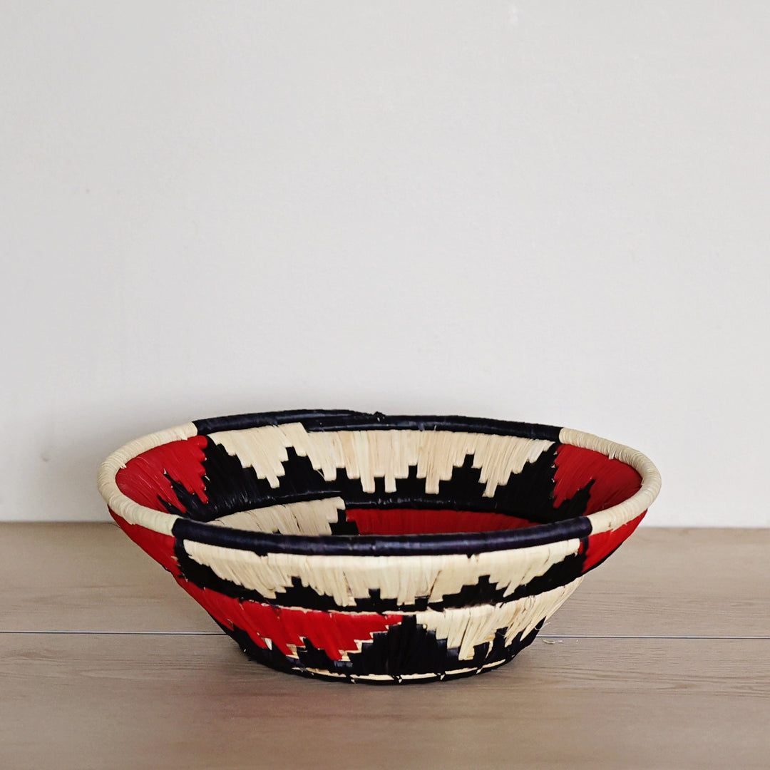 Side view of a Black, Red & Natural Bukedo and Raffia bowl handcrafted in Uganda from banana leaf stalks and palm raffia.