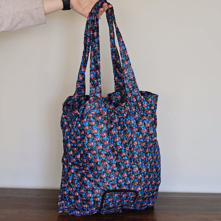 Floral-patterned tote bag held by a person against a plain background