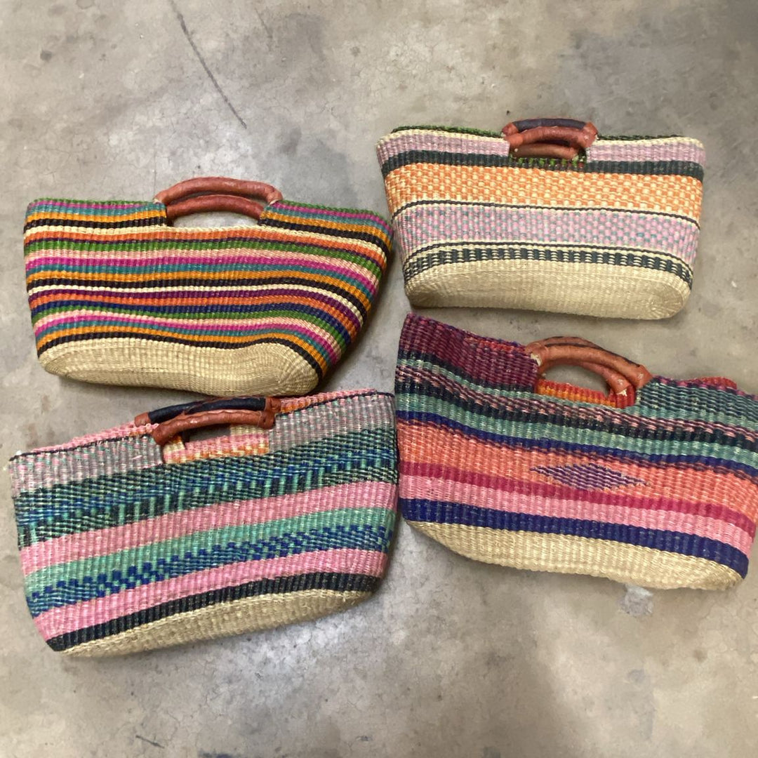 Four colorful woven bags on a concrete floor