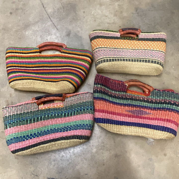 Four colorful woven bags on a concrete floor