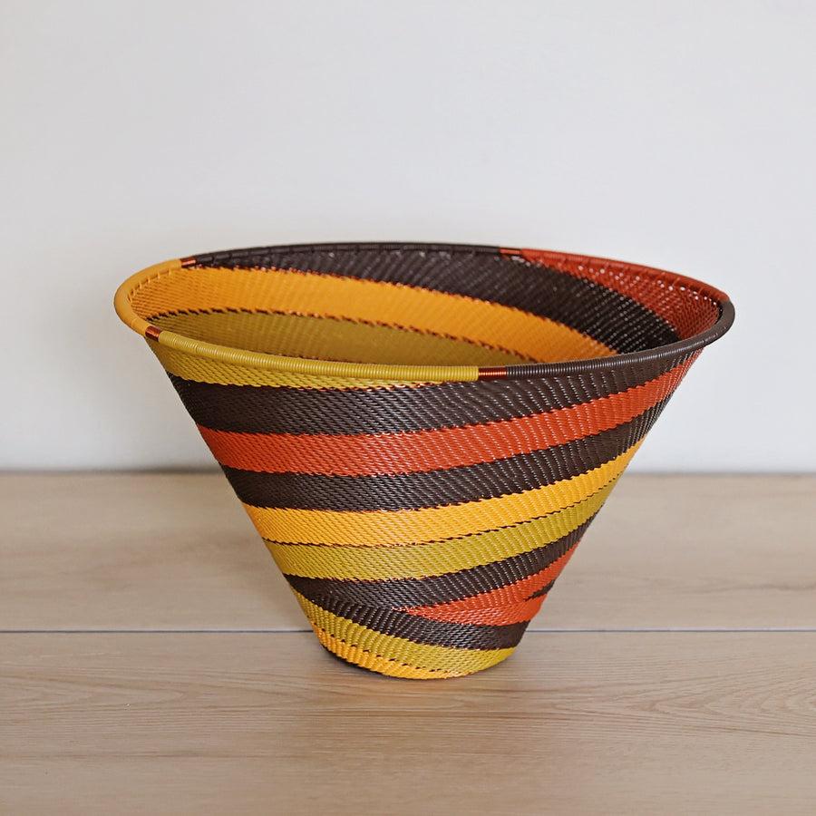 Dark Earth Zulu Medium Deep Funnel Bowl handwoven in South Africa with rich brown, rust, golden yellow, and olive tones.