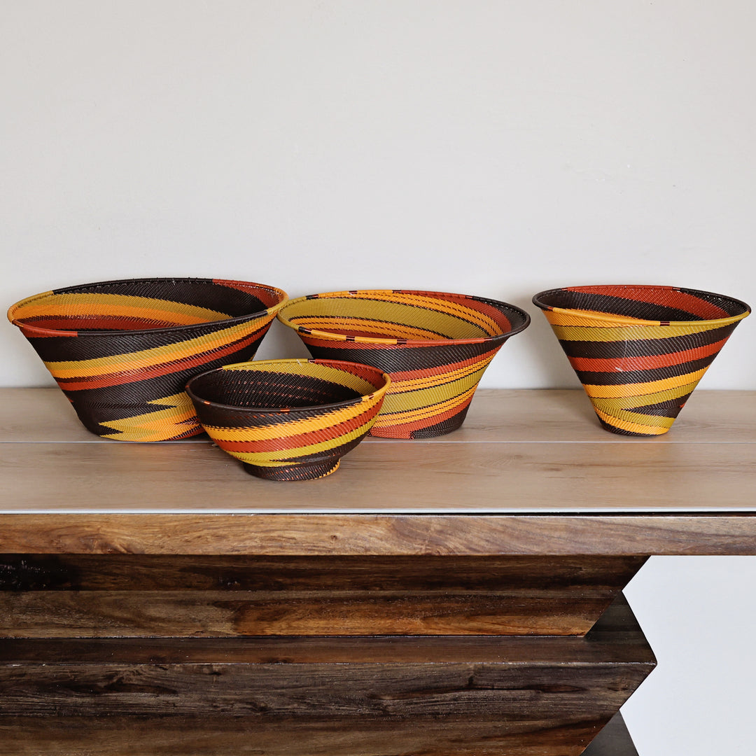 Side view of a Dark Earth Zulu Medium Deep Funnel Bowl featuring warm earth tones and intricate handwoven wire craftsmanship by South African artisans.