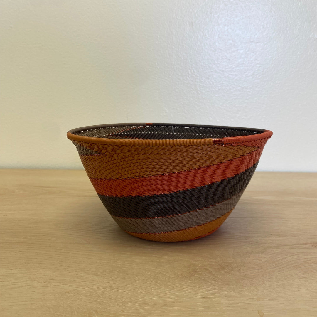 Handwoven Dark Earth Zulu deep bowl wire basket from South Africa featuring brown, burnt orange, ochre and golden yellow stripes.