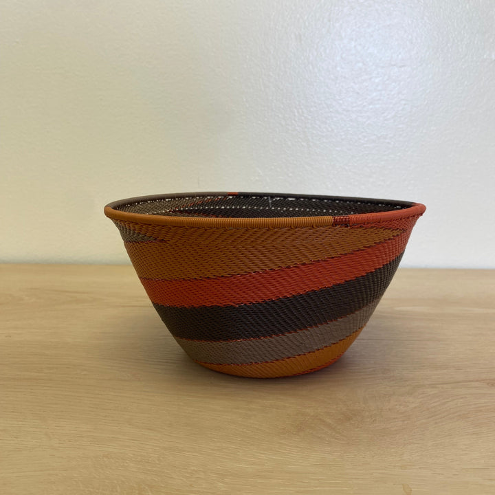 Handwoven Dark Earth Zulu deep bowl wire basket from South Africa featuring brown, burnt orange, ochre and golden yellow stripes.
