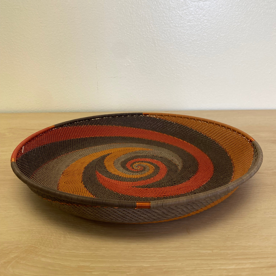 Dark Earth Zulu large tray wire basket handwoven in South Africa with deep brown, rust, orange and golden yellow woven patterns.
