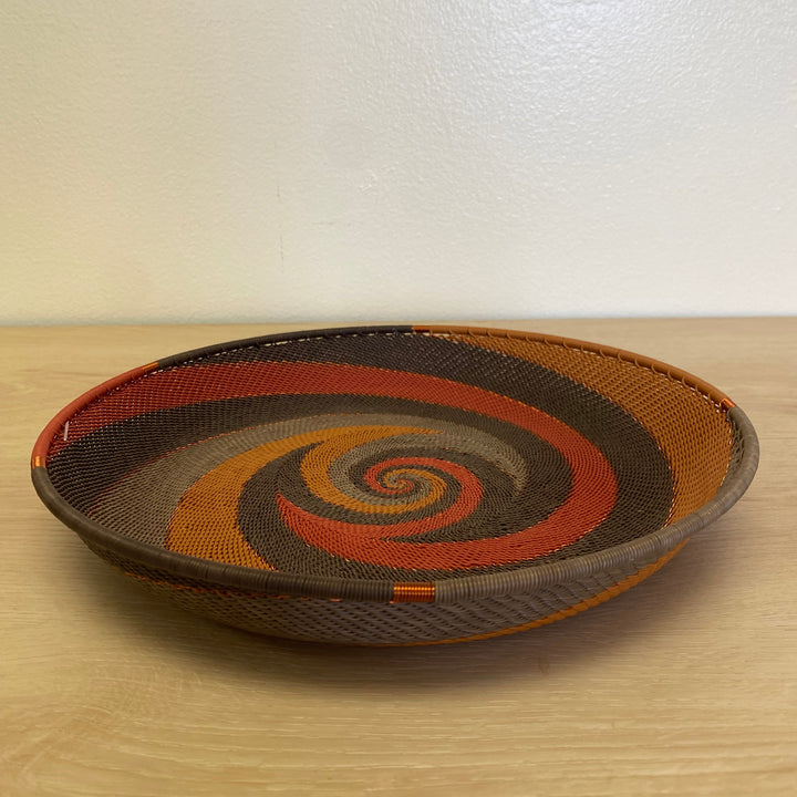 Dark Earth Zulu large tray wire basket handwoven in South Africa with deep brown, rust, orange and golden yellow woven patterns.