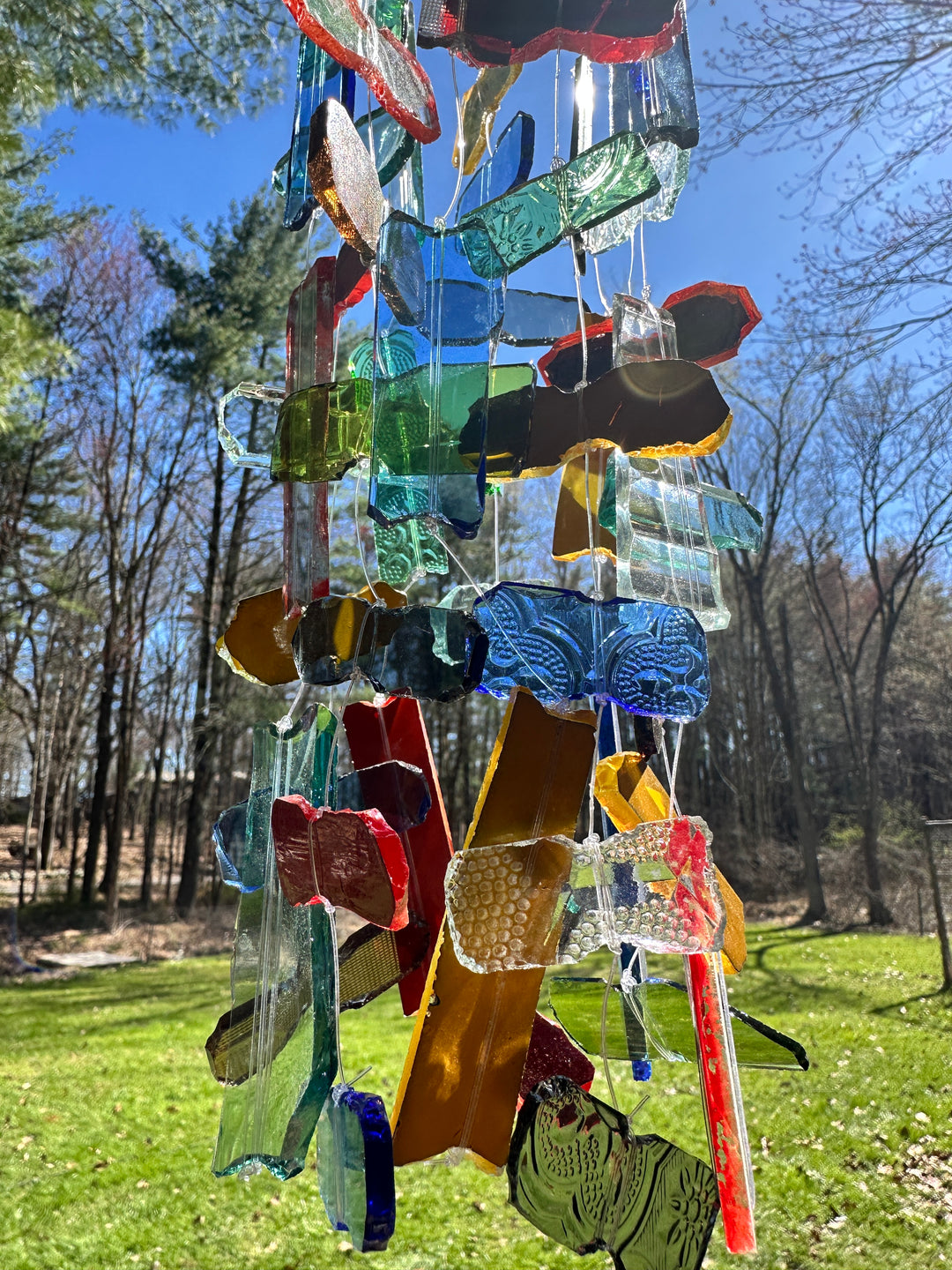 Colorful glass wind chime details with trees in the background, handmade in Kenya.