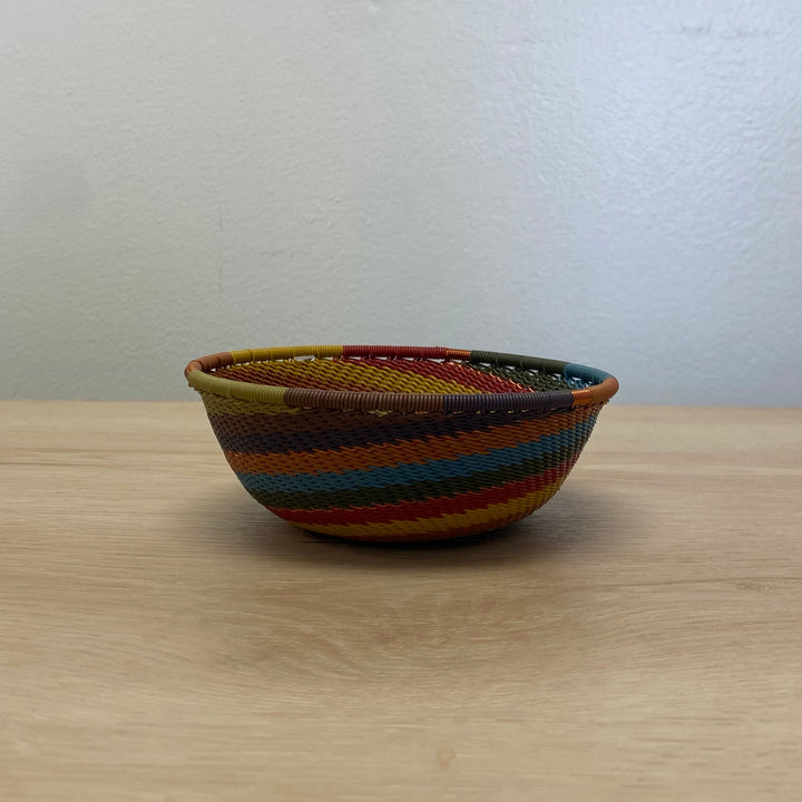 Artisan-made Earthy Rainbow Zulu small wide basket with concentric stripes in warm natural-inspired colors.