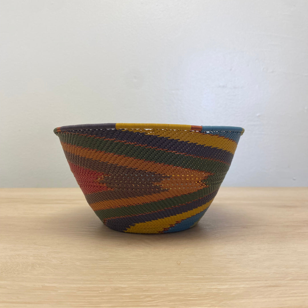 Handwoven South African deep wire bowl featuring the Earthy Rainbow palette and intricate striped weaving.