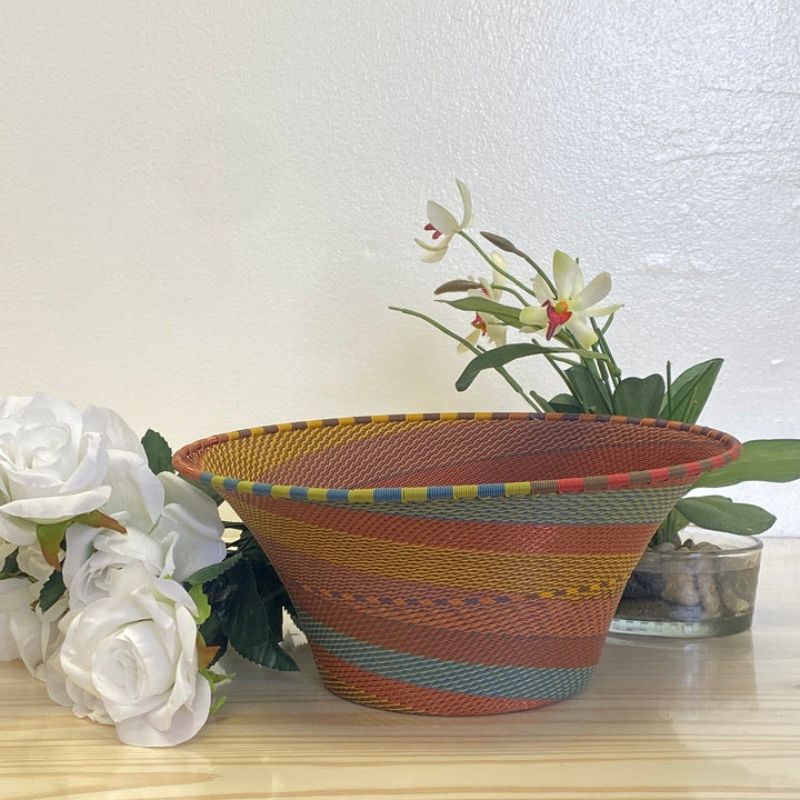 Zulu wire large flared bowl basket with a handwoven spiral design in rust, ochre, muted blue, olive and burgundy.
