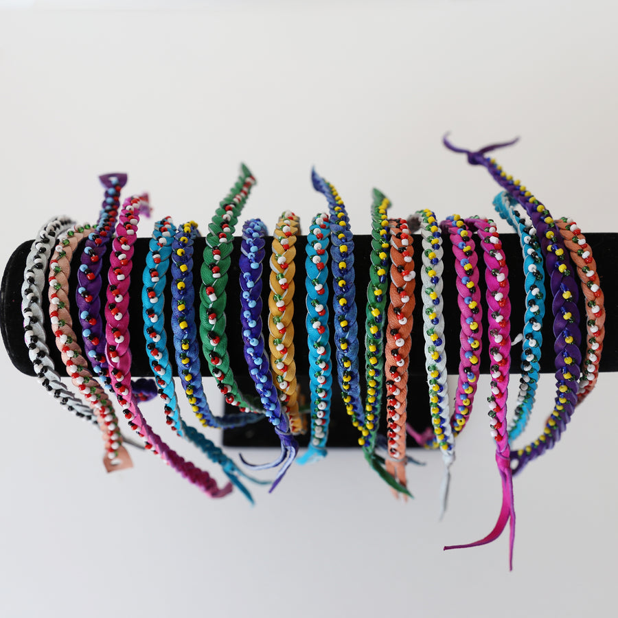 A set of twelve fair trade leather bracelets in assorted colors and sizes, handmade by Kenyan artisans.