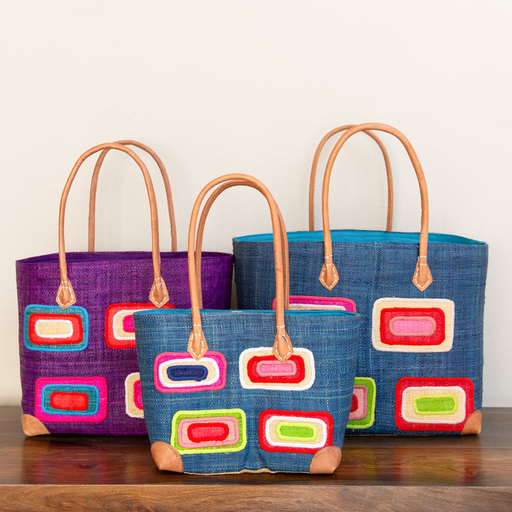 Three, fair-trade, colorful bags with geometric patterns on a wooden surface against a white background.