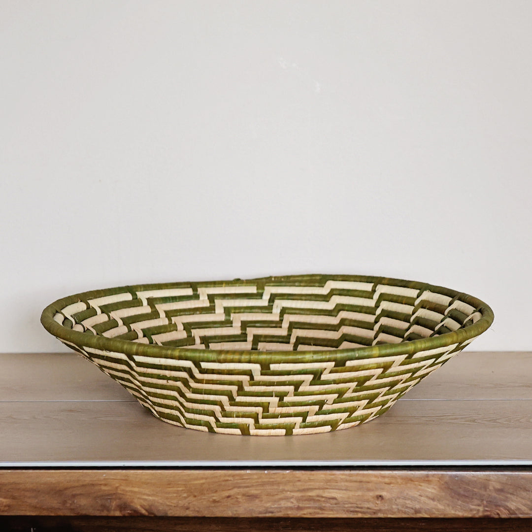 Side view of a Green & White Bukedo and Raffia bowl handcrafted in Uganda from banana leaf stalks and palm raffia with woven green and white patterns.
