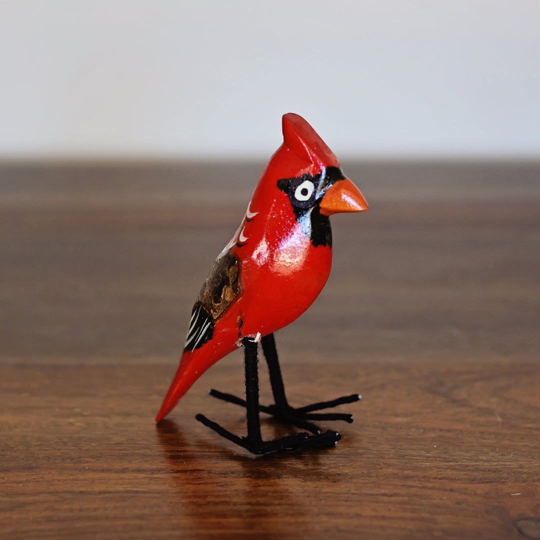 Red cardinal bird figurine on a wooden surface, handmade in Africa by fair-trade artisans. 