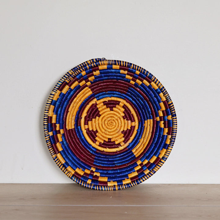 Handwoven Indigo Mosaic Bukedo and Raffia bowl handmade in Uganda featuring deep indigo, golden ochre, and burgundy woven patterns for fair trade home décor.