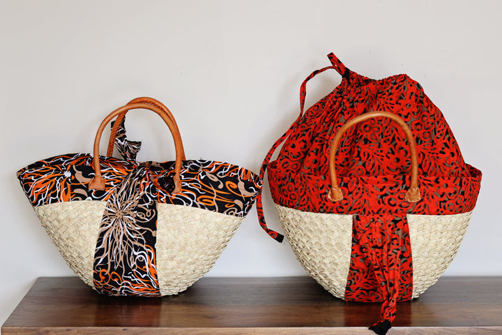 Large Kikapu Janet basket tote handmade in Kenya with woven palm leaf, African fabric, and leather handles.