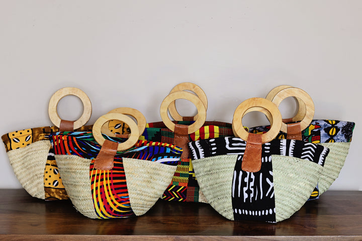 Small Kikapu Janet Tote handmade in Kenya with woven palm leaf, assorted African fabric, and wooden handles.