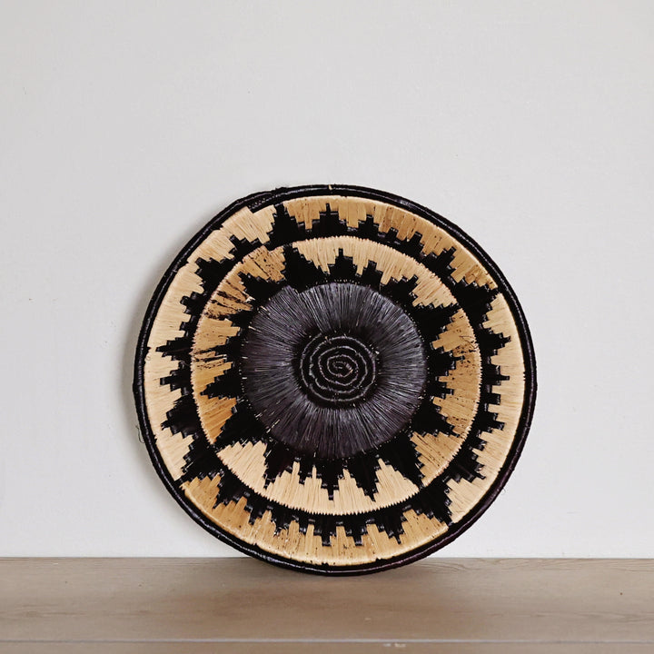 Handwoven Midnight Sun Bukedo and Raffia bowl handmade in Uganda featuring a bold black, charcoal, and natural geometric pattern for fair trade home décor.