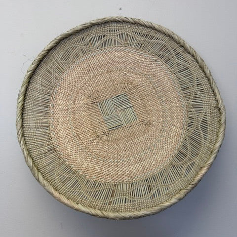 Rustic Binga winnowing bowl woven from palm leaves used as a decorative tray or centerpiece, in a natural color.