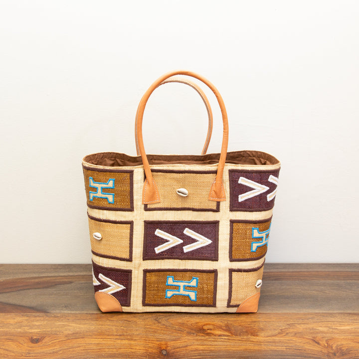 Fair-trade, neutral colored tote bag with geometric pattern, sitting on a wooden surface.