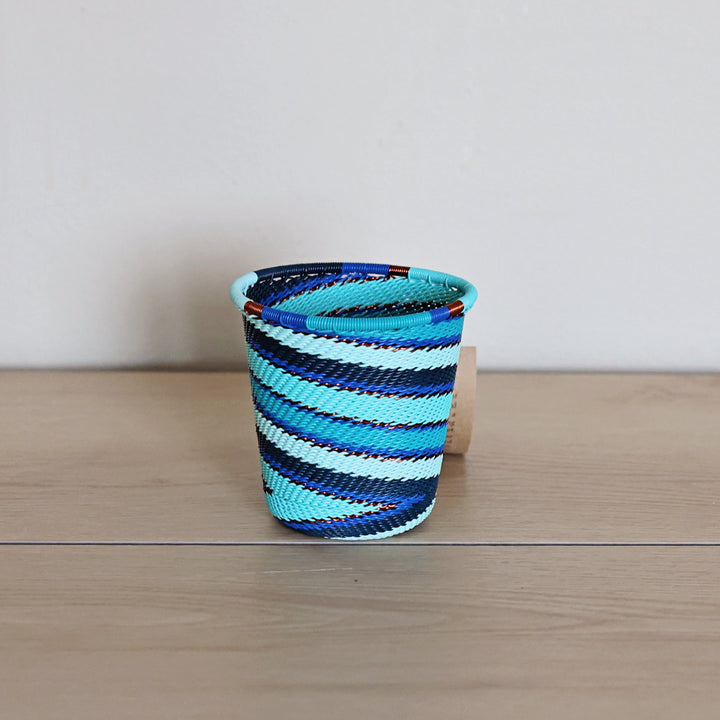 Handwoven Ocean Zulu wide base cup basket with graphic navy, turquoise and aqua woven patterns.