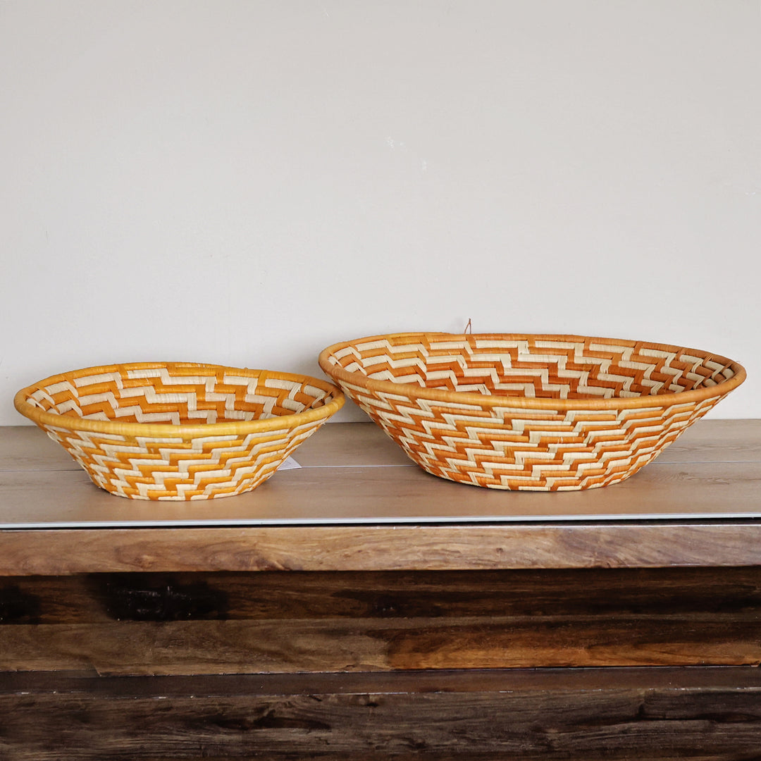 Side view of an Orange & White Bukedo and Raffia bowl handcrafted in Uganda from banana leaf stalks and palm raffia with vibrant orange and white weaving.
