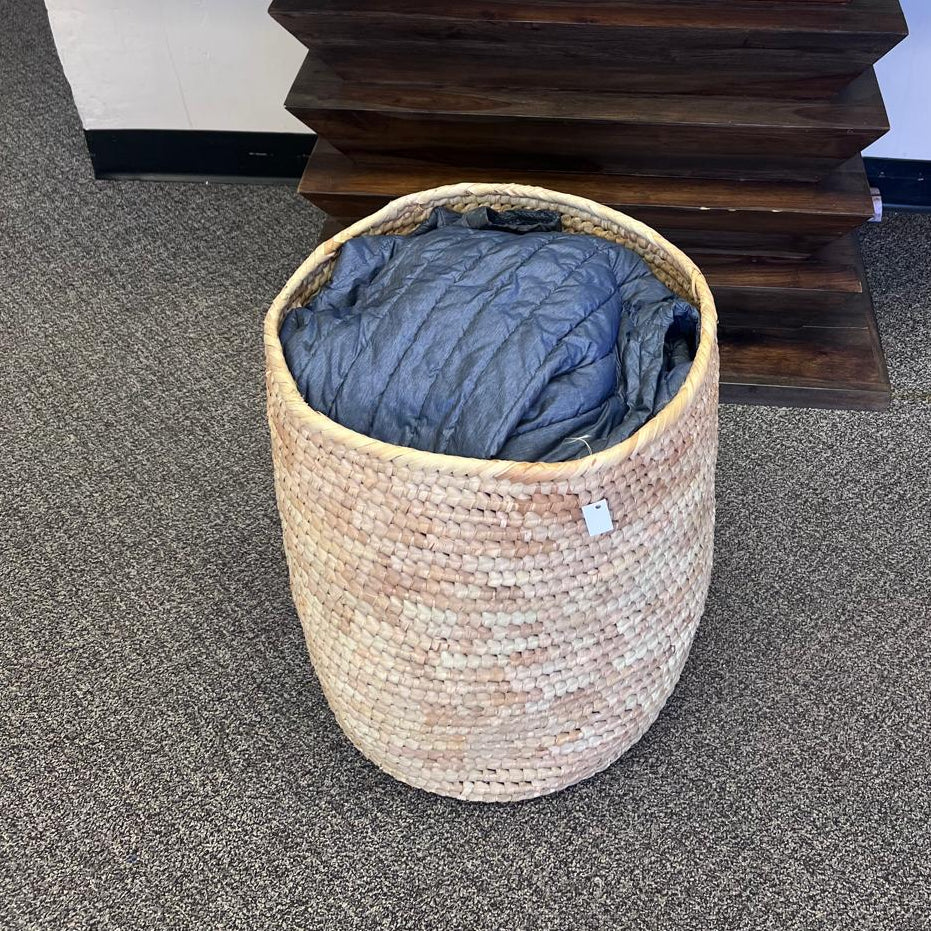 XL palm leaf storage basket used as a laundry hamper in a bedroom, handcrafted from sustainable materials.