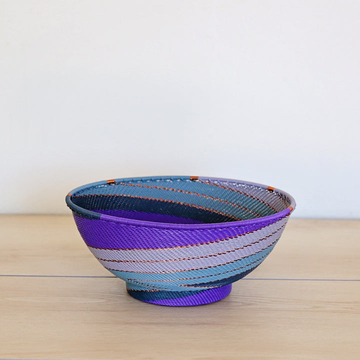 Purple Zulu Bowl with Base handwoven in South Africa with layered shades of purple in a diagonal stripe pattern.