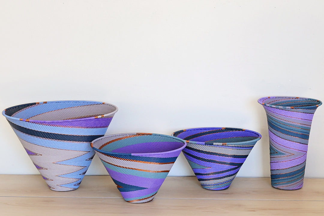 Purple Zulu Medium Deep Funnel Bowl handwoven in South Africa with layered shades of purple in a diagonal stripe pattern.