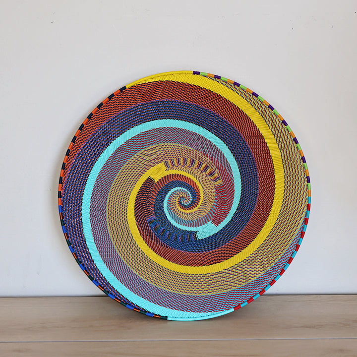 Rainbow Zulu Extra Large Shallow Basket handwoven in South Africa with vibrant multicolor diagonal stripes and copper wire accents.