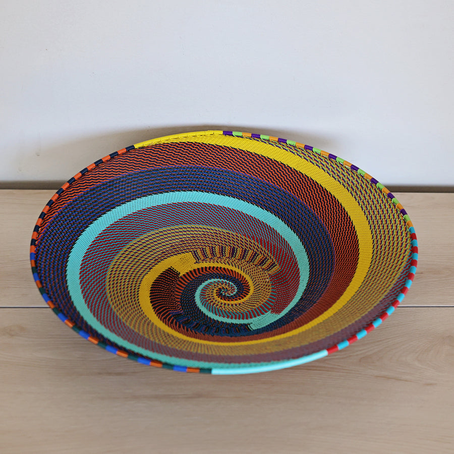 Rainbow Zulu Large Shallow Basket handwoven in South Africa with vibrant multicolor diagonal stripes and copper wire accents.