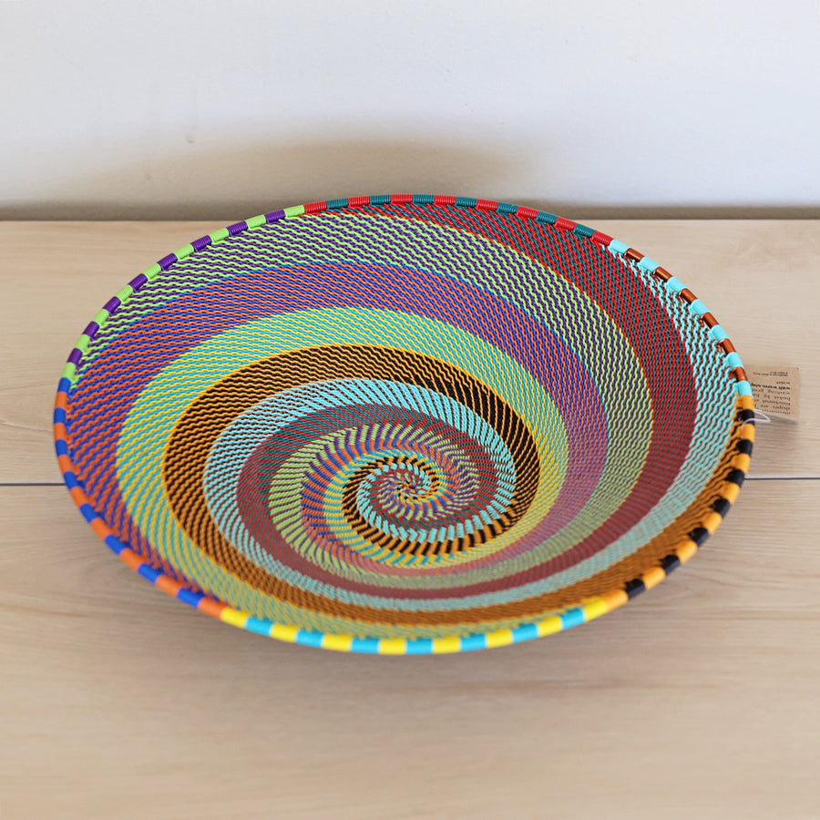 Rainbow Zulu Medium Shallow Basket handwoven in South Africa with vibrant multicolor diagonal stripes and copper wire accents.