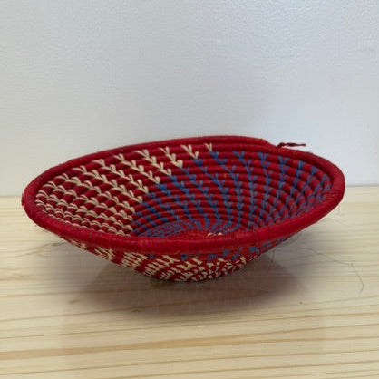 Handwoven red spiral raffia bowl featuring an intricate artisan-woven pattern.