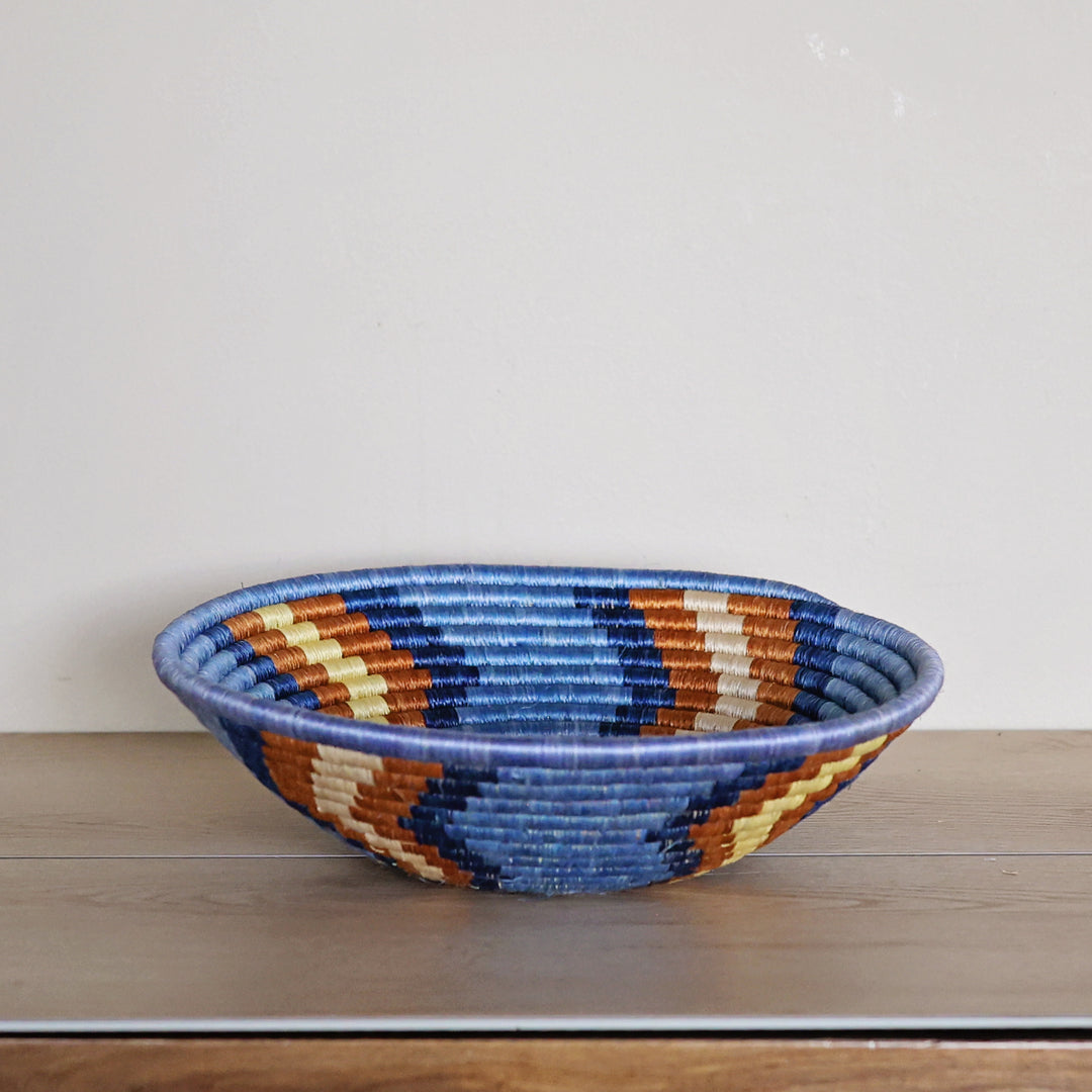 Side view of a handcrafted Rwanda sisal basket in blue, red, and white, woven by fair trade artisans for African home décor.