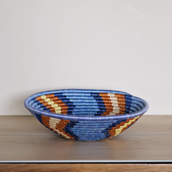 Side view of a handcrafted Rwanda sisal basket in blue, red, and white, woven by fair trade artisans for African home décor.