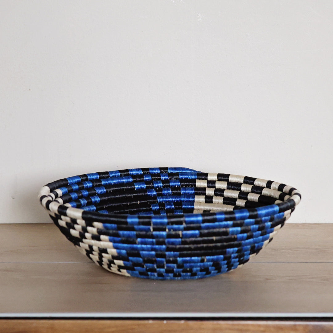 Side view of a handcrafted Rwanda sisal basket in bright blue, black, and white, woven by fair trade artisans for African home décor.
