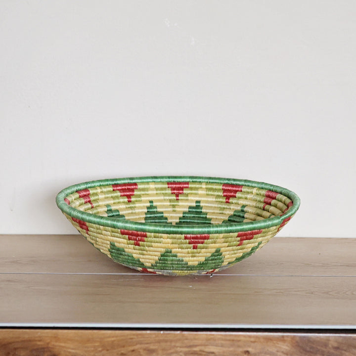 Side view of a handcrafted Rwanda sisal basket in green, light blue, and red, woven by fair trade artisans for African home décor.