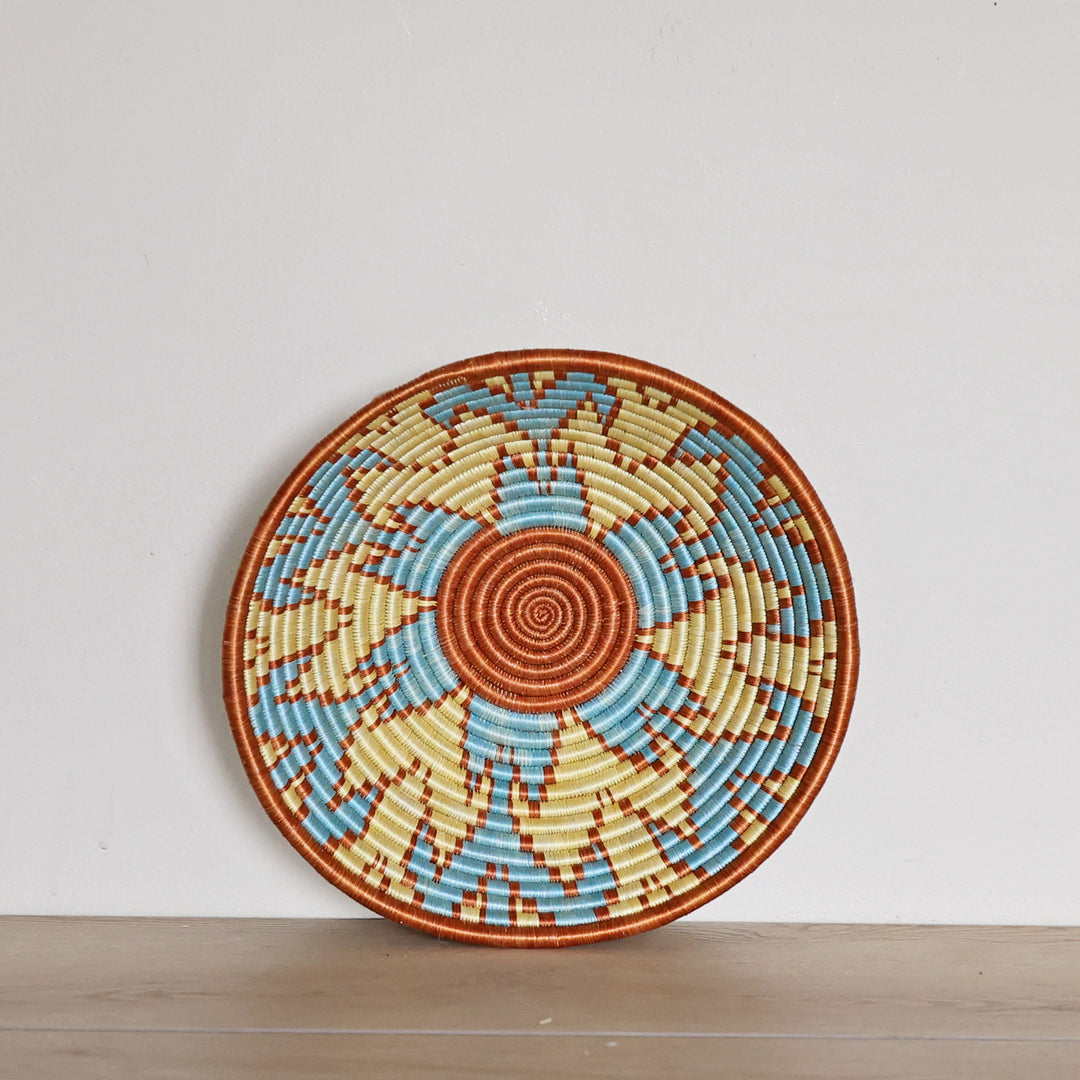 Handwoven Rwanda Sisal Basket in light blue, orange, and light yellow colors. Perfect for hosting and decorating. 