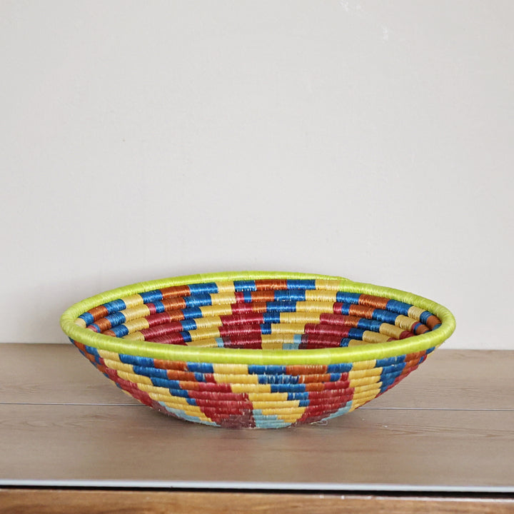 Side view of a handcrafted Rwanda sisal basket with a colorful spiral design woven by fair trade artisans in Rwanda.