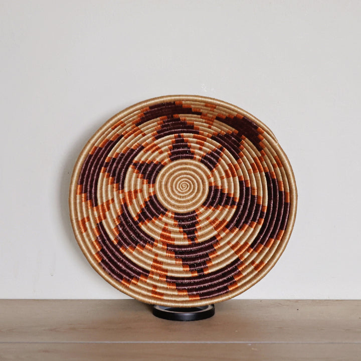 Handwoven Rwanda sisal basket in natural, chocolate, and orange geometric patterns for fair trade wall décor and artisan home styling.