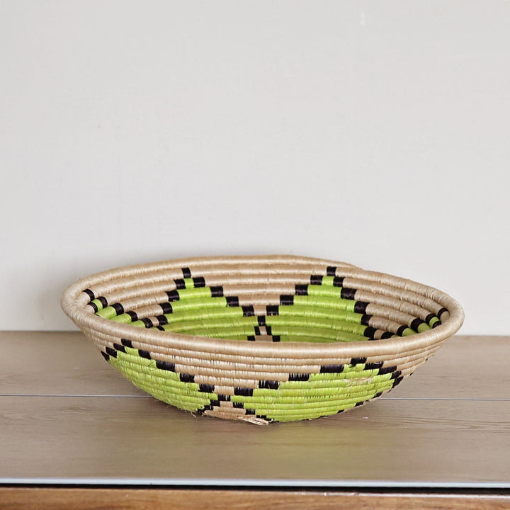 Side view of a handcrafted Rwanda sisal basket featuring a natural and green flower design woven by fair trade artisans in Rwanda.