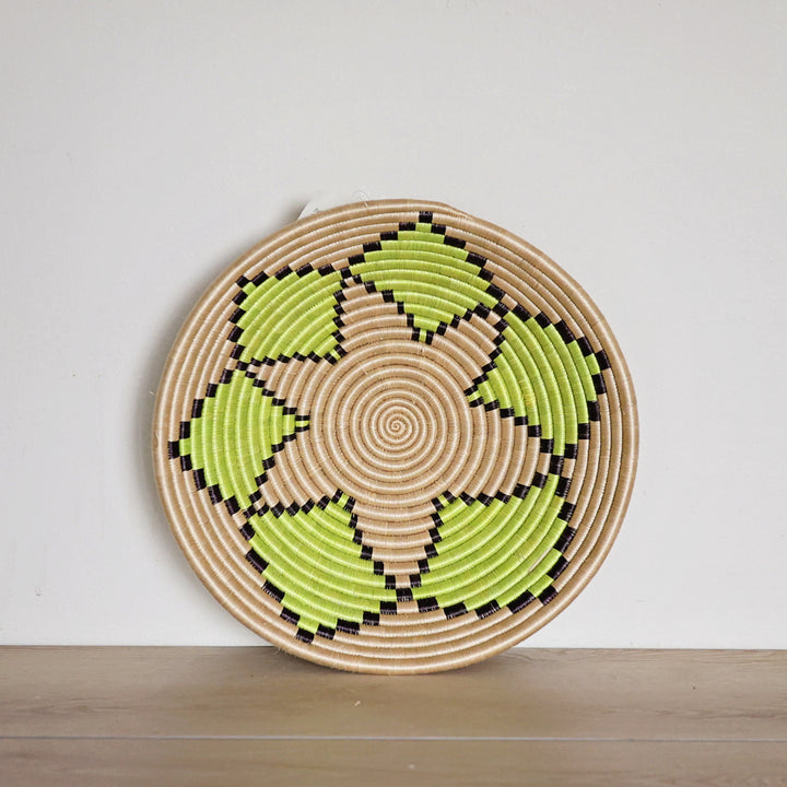 Handwoven Rwanda sisal basket with a natural background and green floral pattern viewed from above for fair trade wall décor.