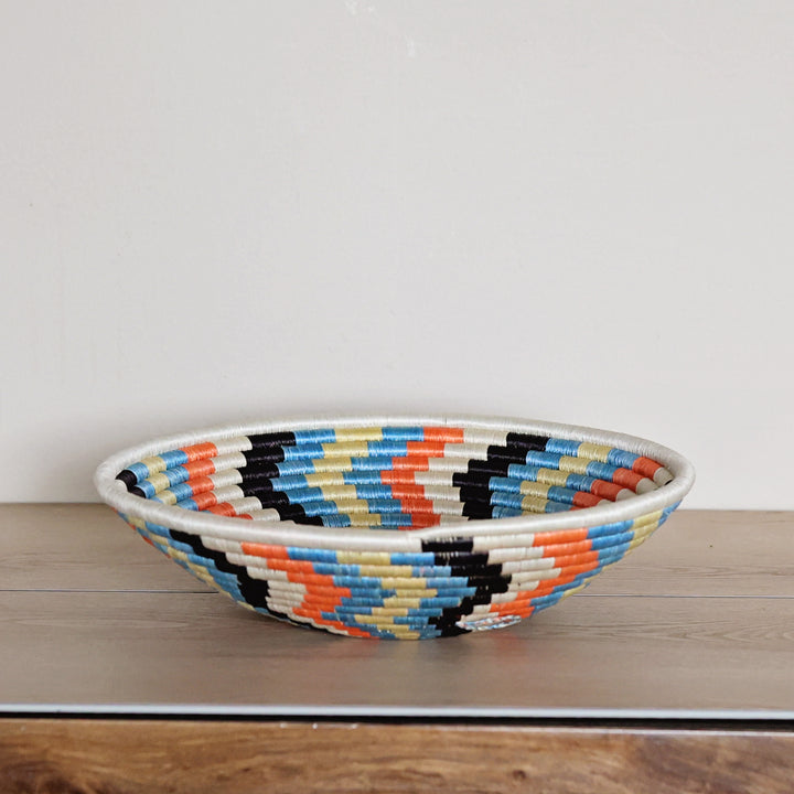 Side view of a handcrafted Rwanda sisal basket in white and multicolor, woven by fair trade artisans for African home décor.