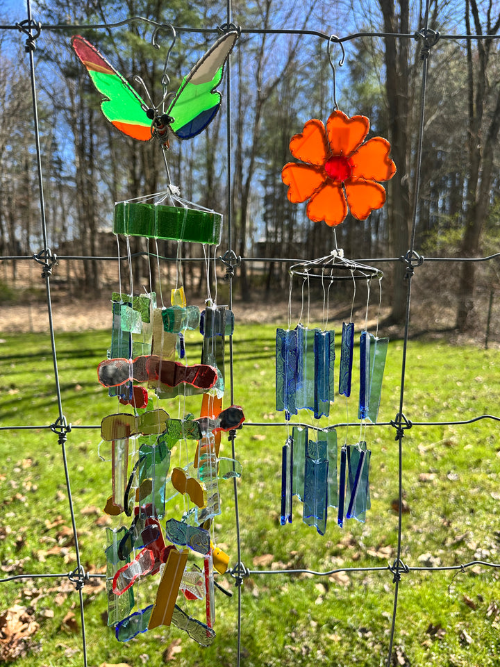 Colorful glass wind chime with flowers and butterflies against a natural background