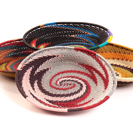 Three hand-woven oval Zulu soapdishes baskets with colorful spiral patterns, displayed on a clean white background.