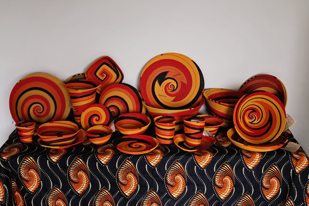 Collection of Sunset Zulu wire baskets handwoven in South Africa in warm red, orange, golden yellow and black spiral patterns.