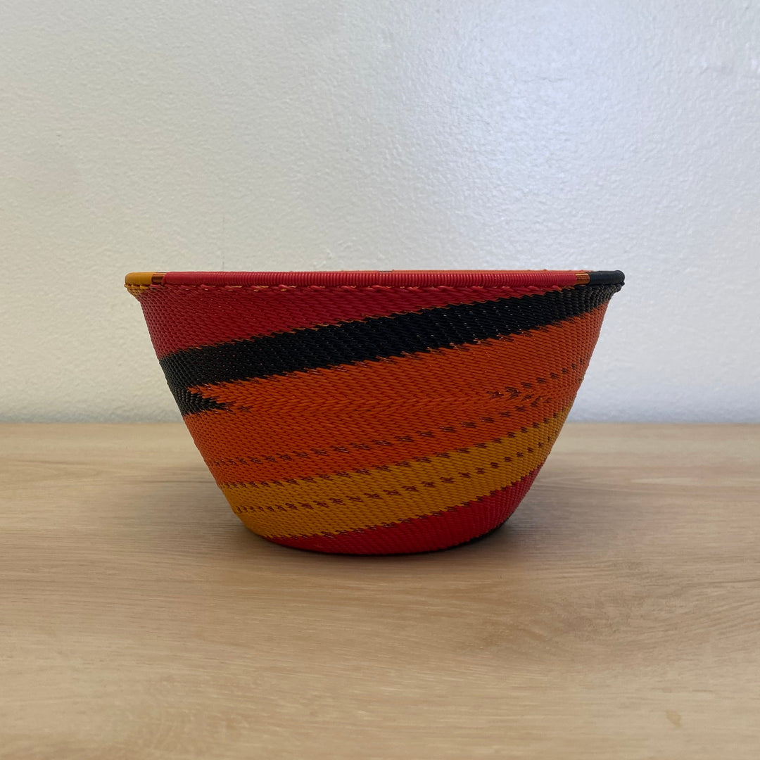 Shallow Sunset Zulu wire deep bowl handwoven in South Africa with warm red, orange, gold and black stripes.