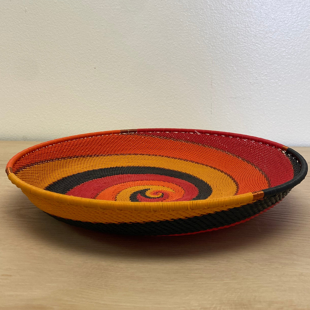 Large tray Sunset Zulu wire bowl handwoven in South Africa with warm red, orange, gold and black stripes.