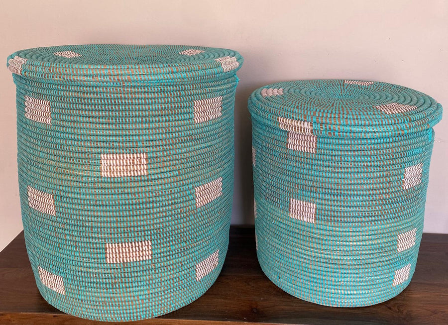 Two turquoise woven baskets with white patterns on them are sold as a set and perfect for use as a hamper.