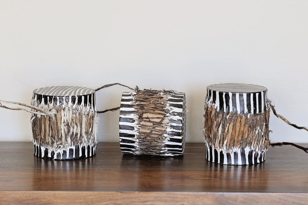 Three decorative, fair-trade drums with black and white zebra patterns on a wooden surface.